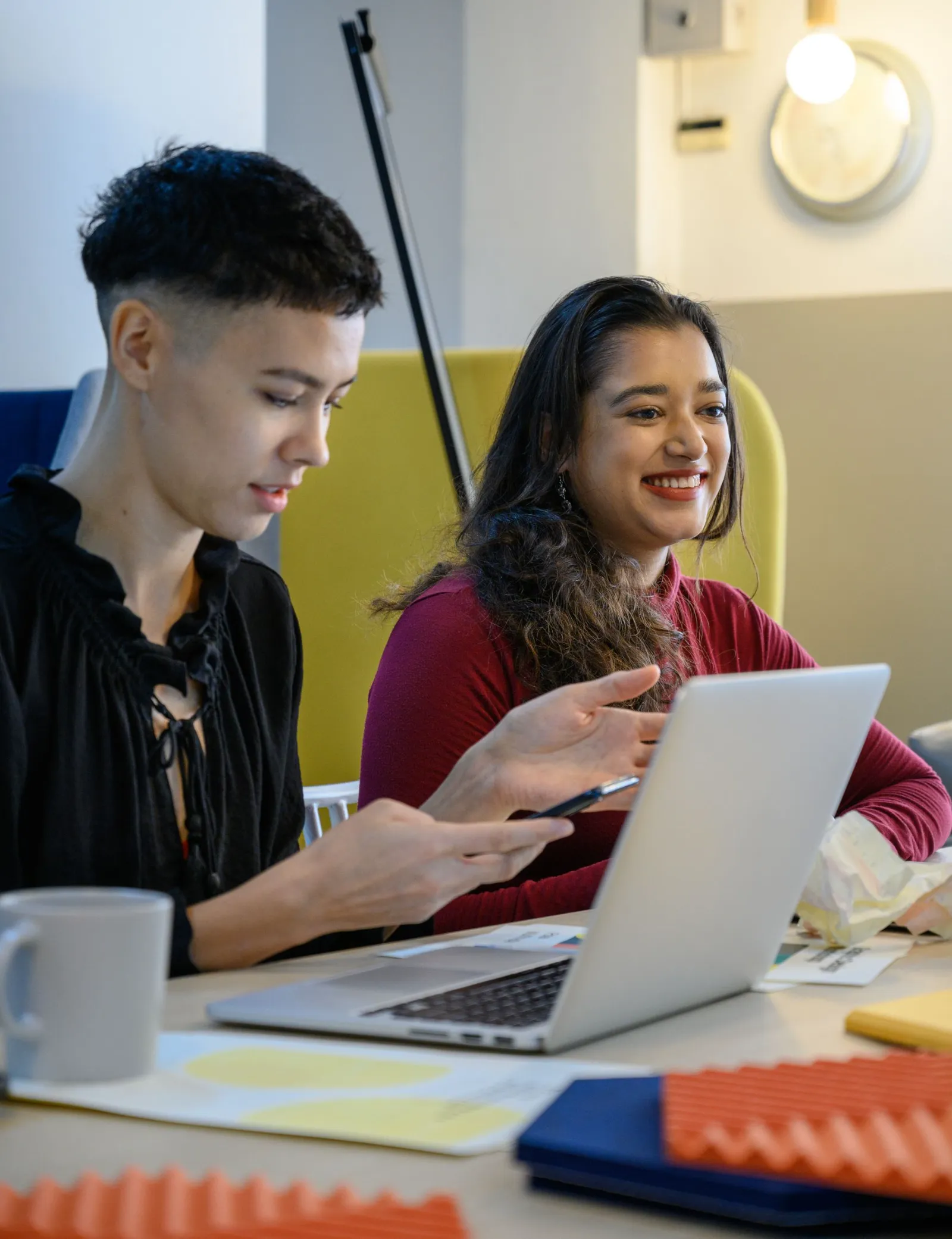 Two young people smiling while working together on a laptop