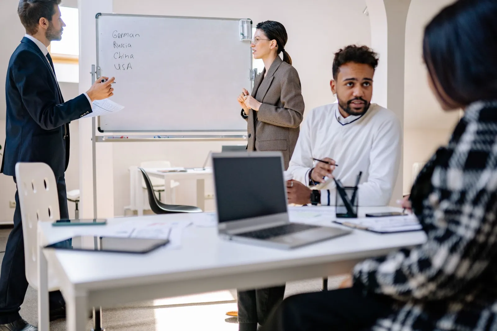 A mentor presenting at a whiteboard to a team with laptops